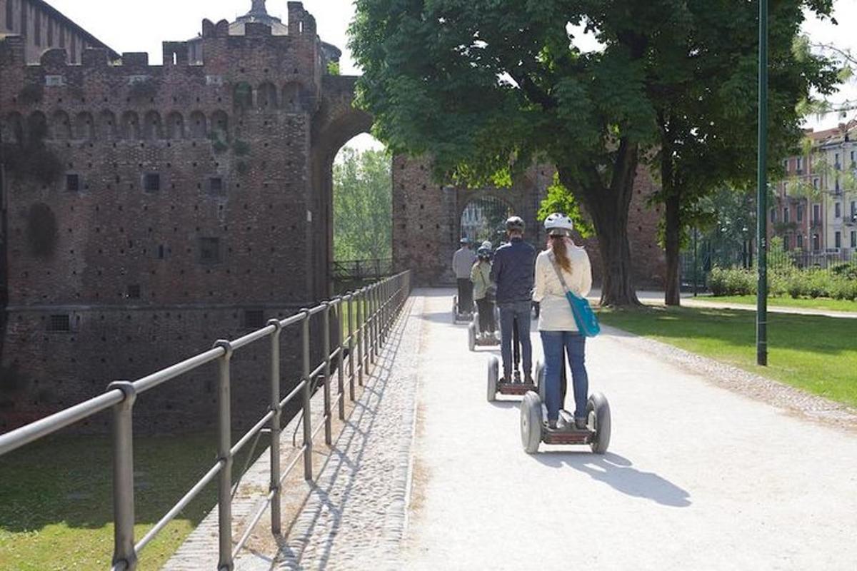 skupina ljudi, ki se vozijo na segwayih pred gradom