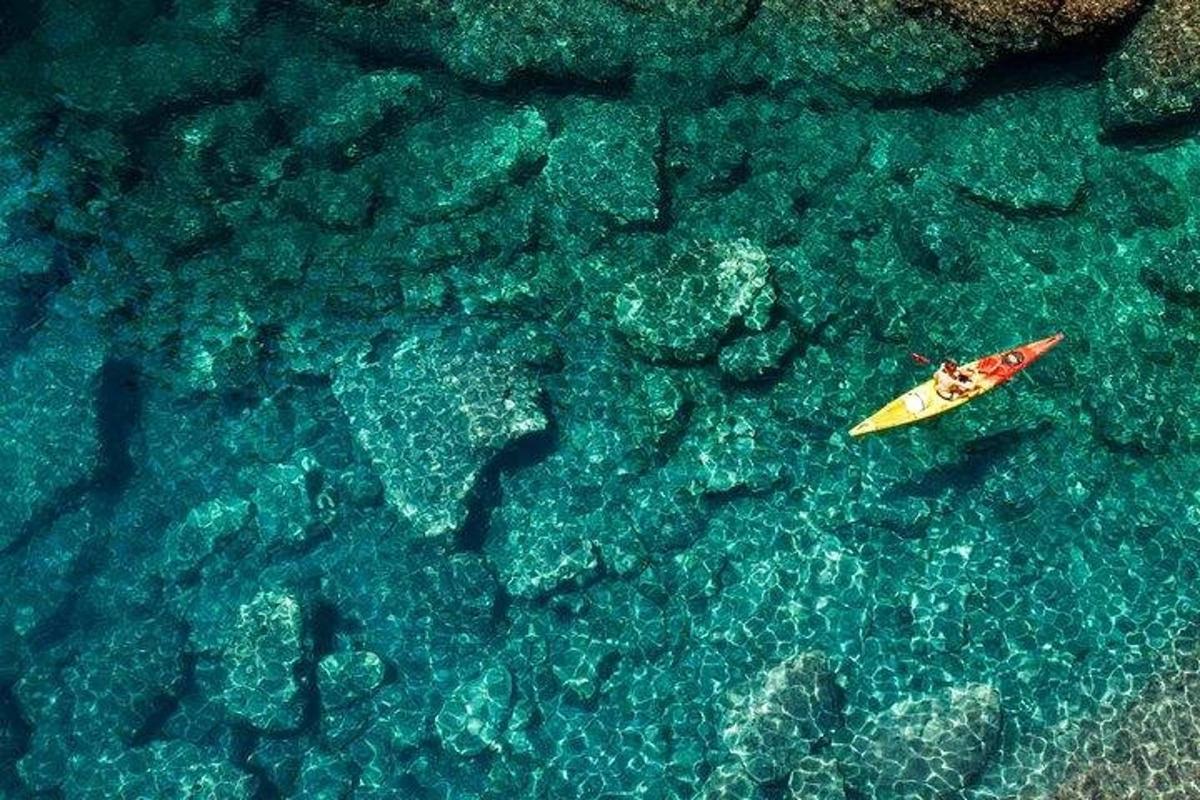 желтая доска для серфинга в воде рядом со скалами