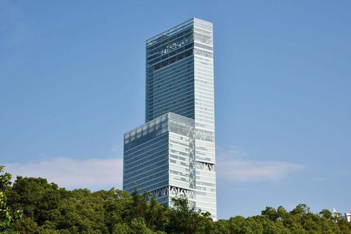 ένα ψηλό γυάλινο κτίριο με δέντρα μπροστά του