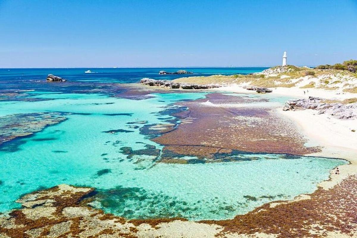 ein Strand mit blauem Wasser und einem Leuchtturm im Hintergrund