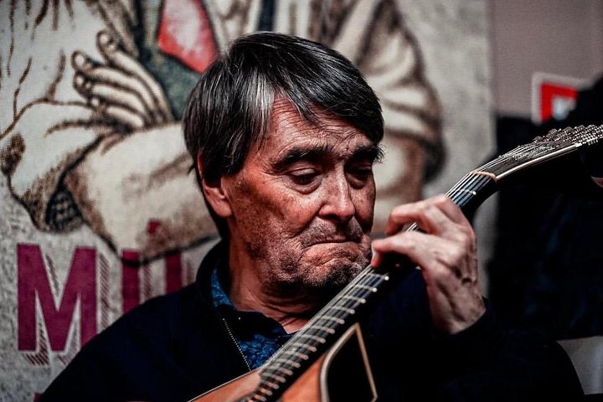 un home tocant una guitarra davant d'una paret