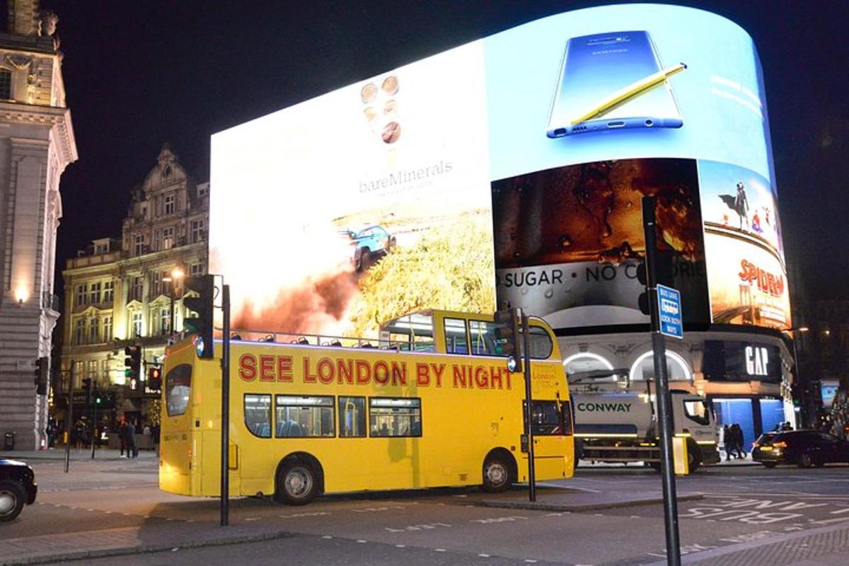 un autobús groc de dos pisos aparcat davant d'un cartell publicitari