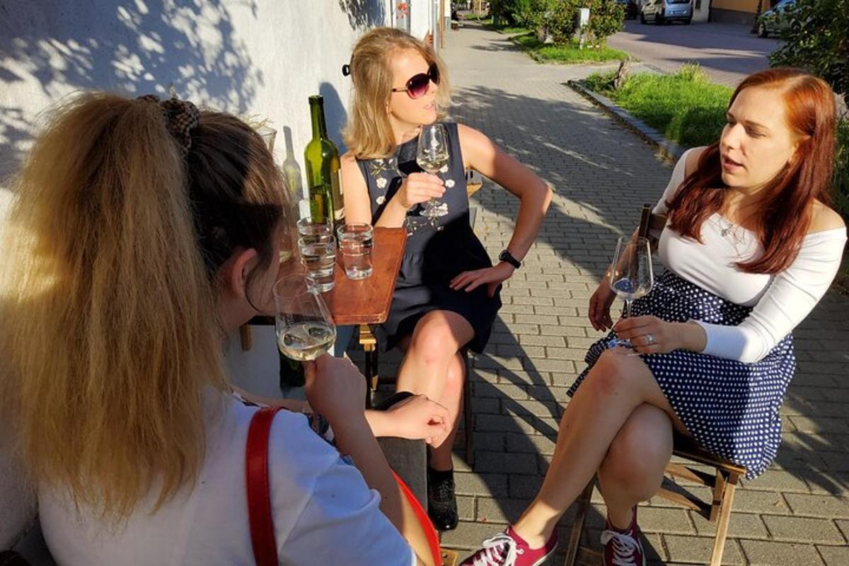 three women sitting around a table with glasses of wine