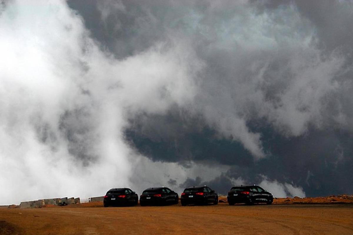 a group of four cars parked under a cloudy sky