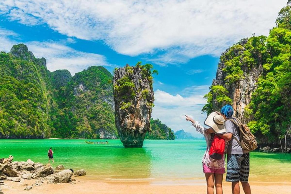 Una pareja parada en la playa con vista a una isla tropical.