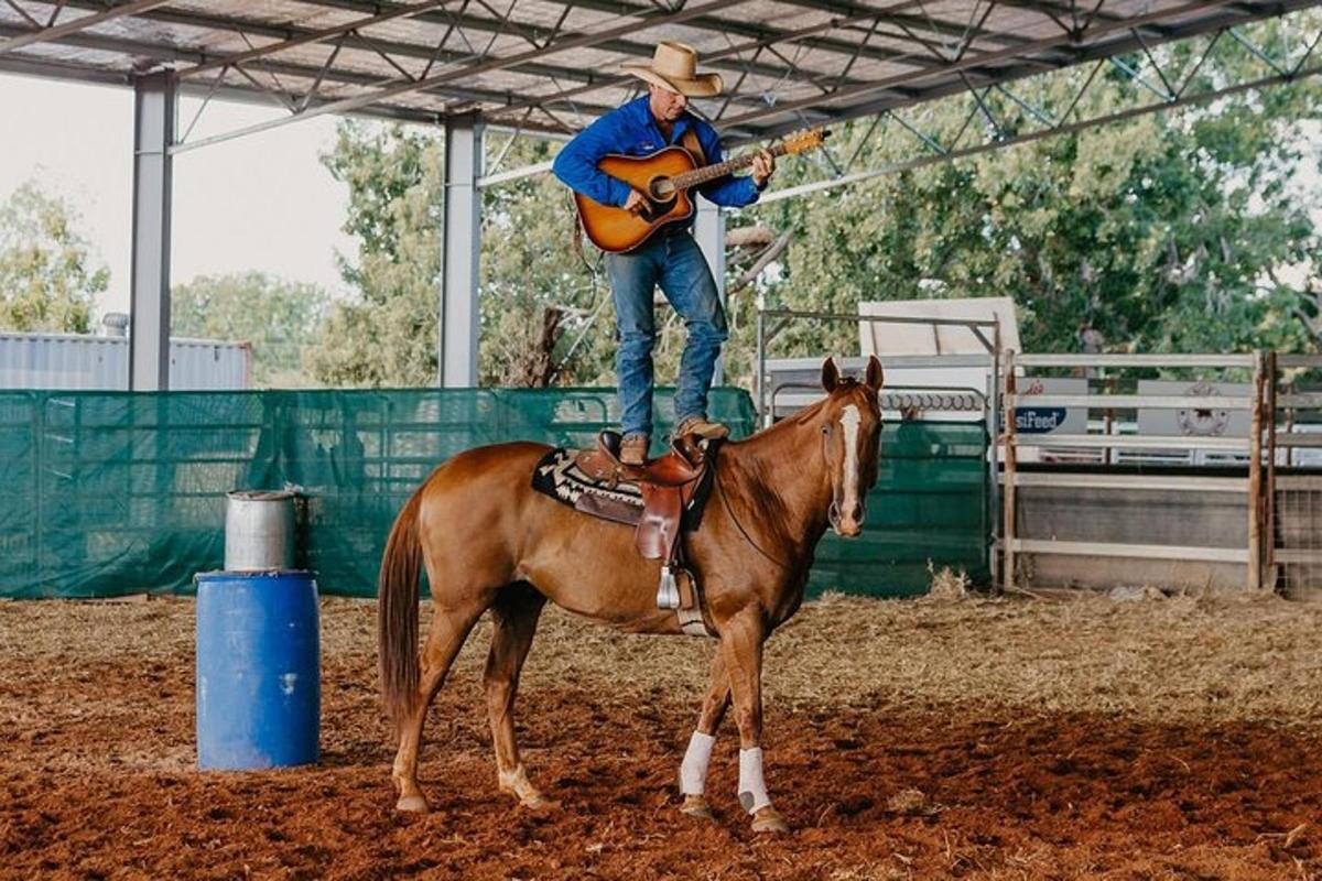 a man sitting on top of a horse with a guitar