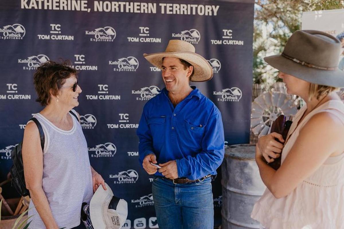 a man in a cowboy hat talking to two women