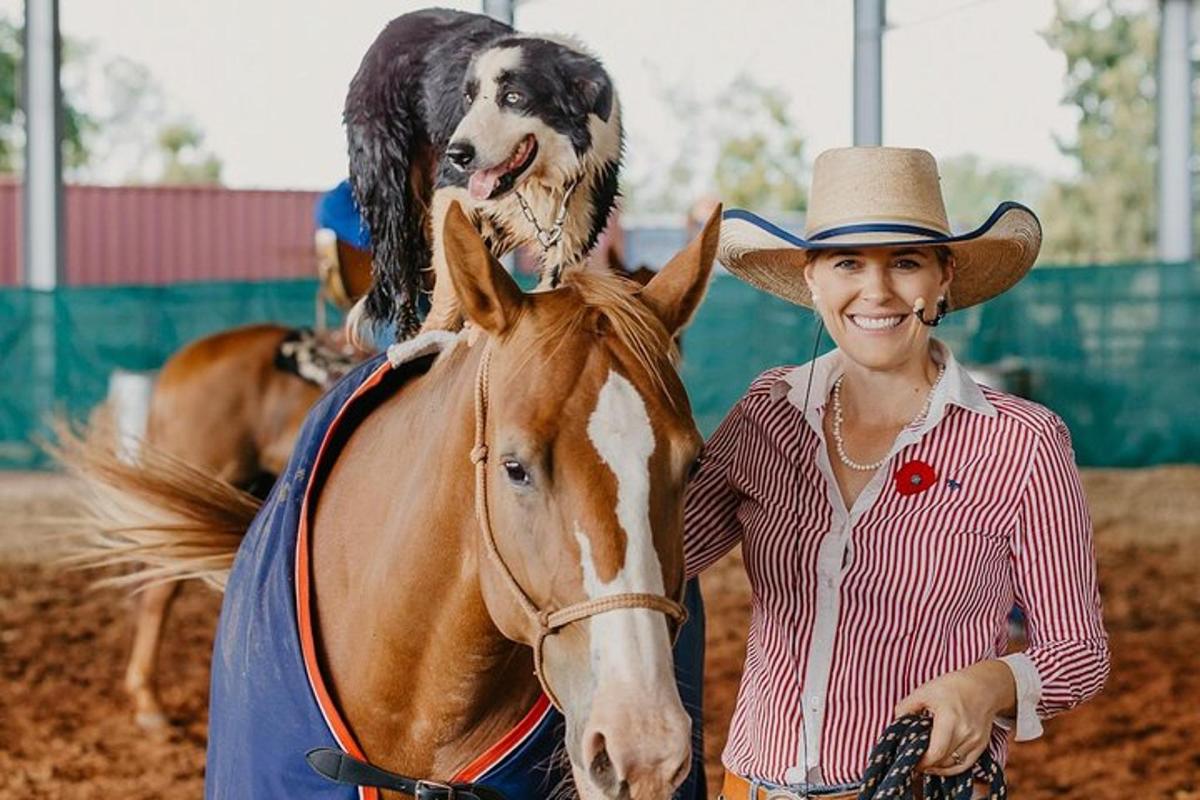 a woman in a cowboy hat and a dog on a horse