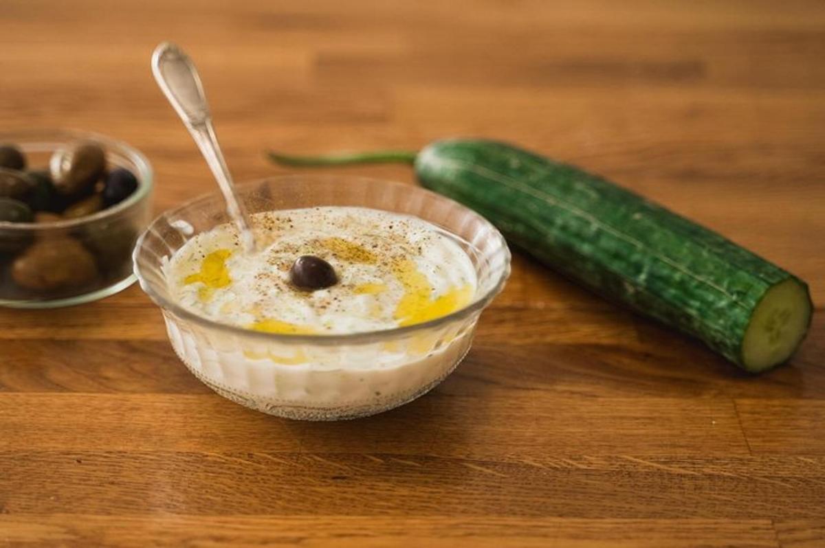 a bowl of dip and a cucumber on a table