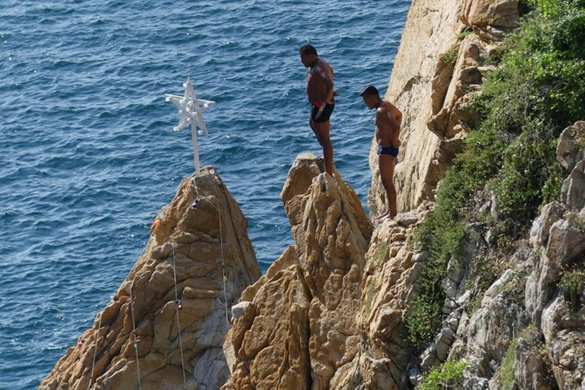 two men are standing on rocks near the ocean