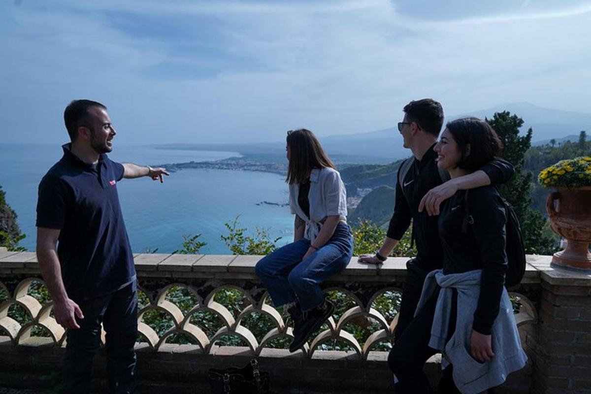 a group of people sitting on a ledge looking at the water