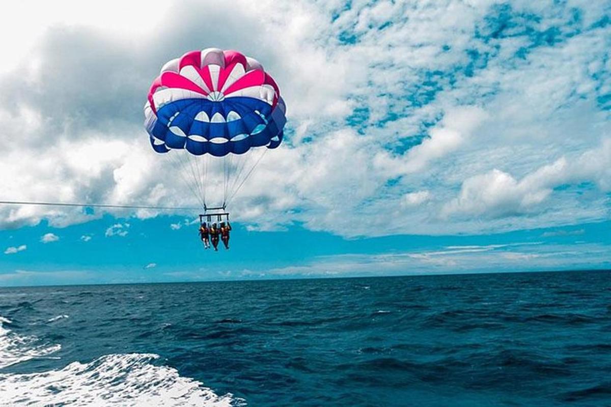a blue and pink parachute flying over the ocean