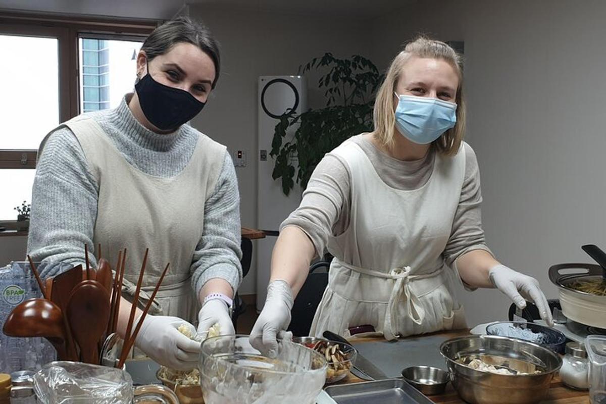 two women wearing masks in a kitchen preparing food