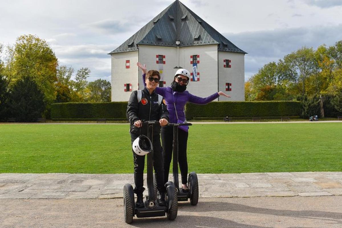 Maður og kona ríða á Segway fyrir framan byggingu