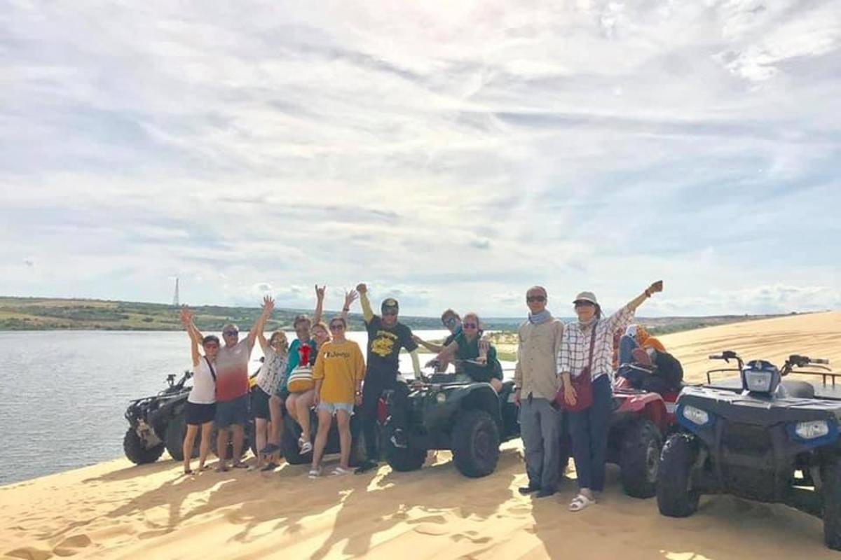 eine Gruppe von Menschen steht im Sand in der Nähe des Wassers