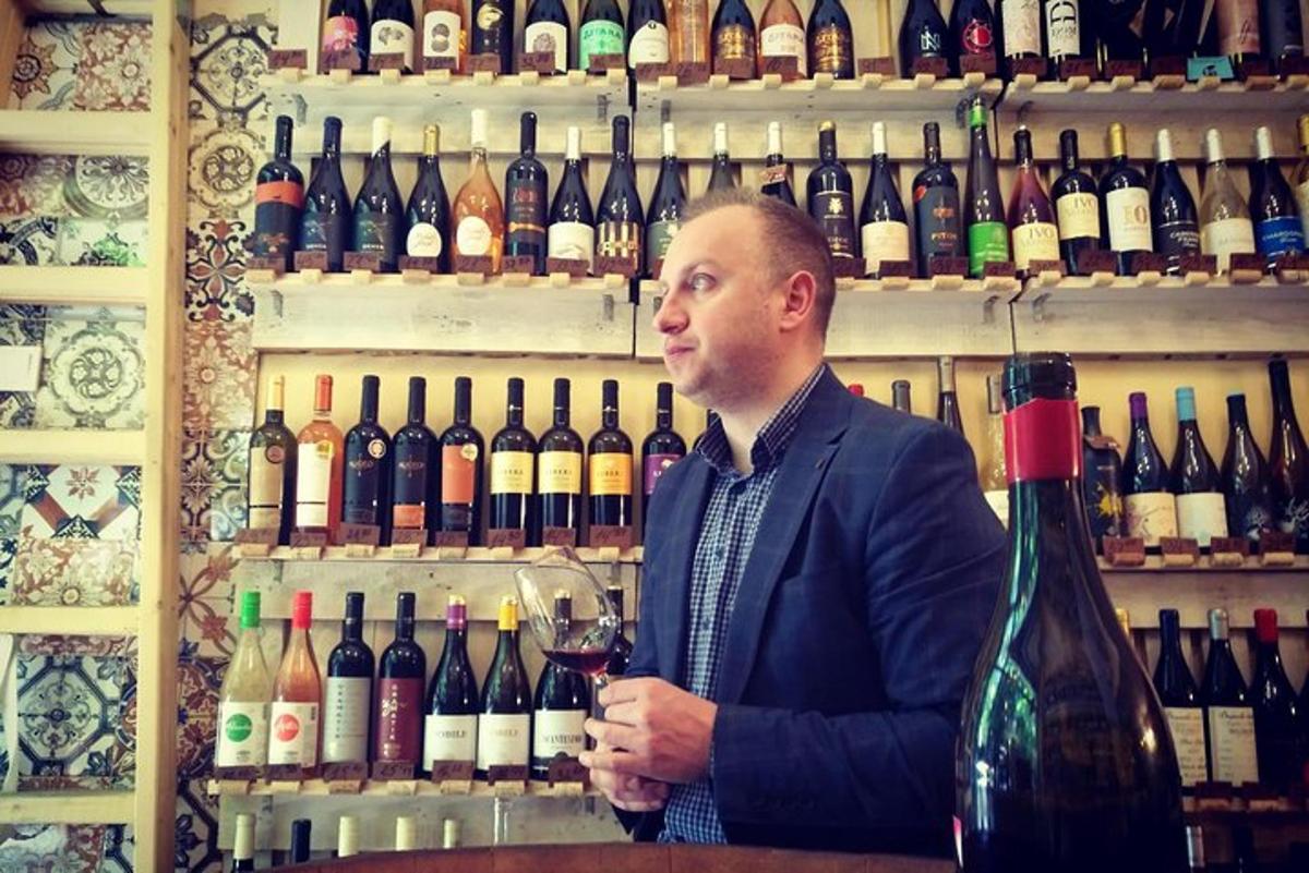 a man standing at a bar with a bottle of wine