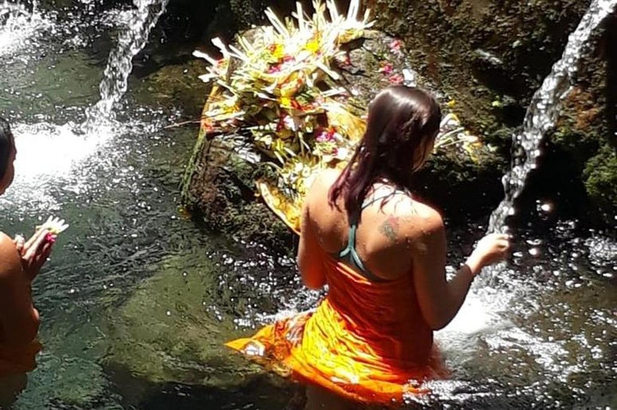 a woman standing in the water near a waterfall