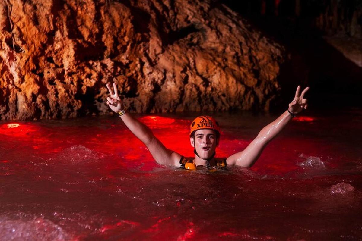 un uomo in acqua con le braccia alzate in una grotta