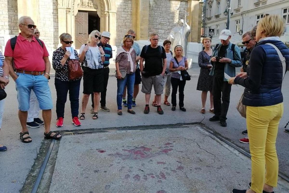 um grupo de pessoas em pé ao redor de um bueiro na rua