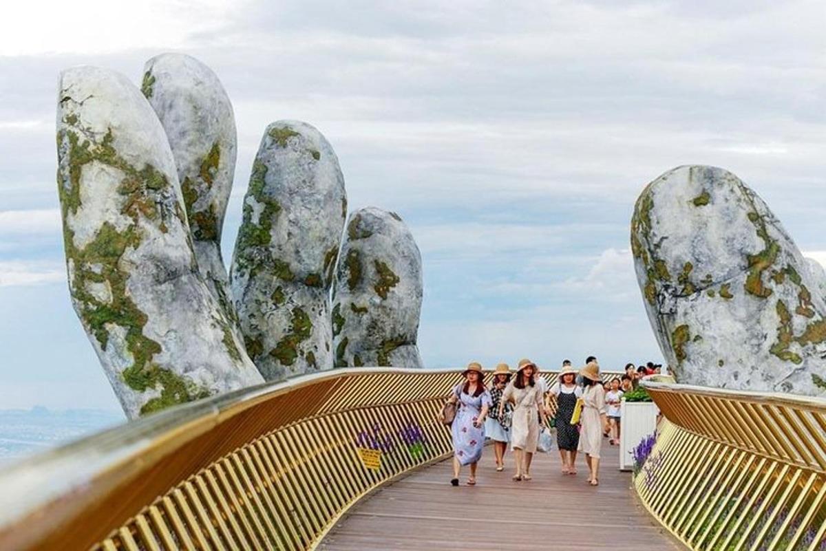 un grup de persones caminant per un pont amb grans mans de pedra