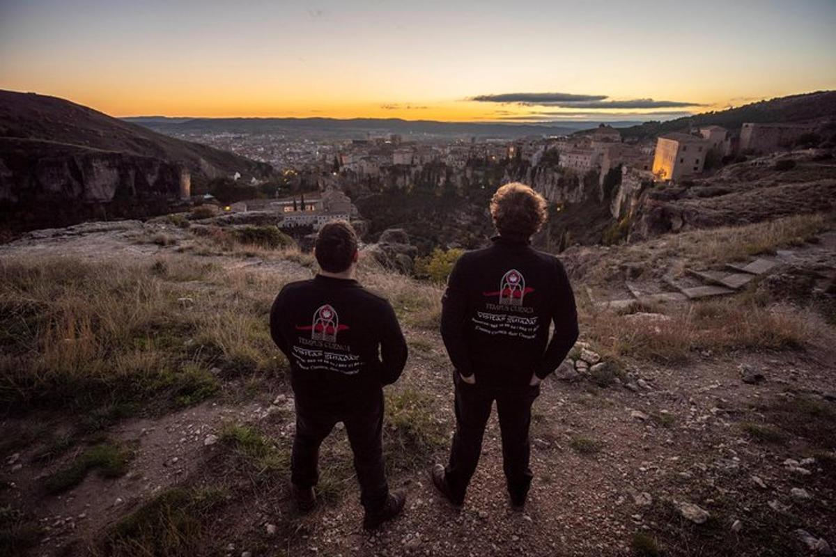 two men standing on a hill looking at a city