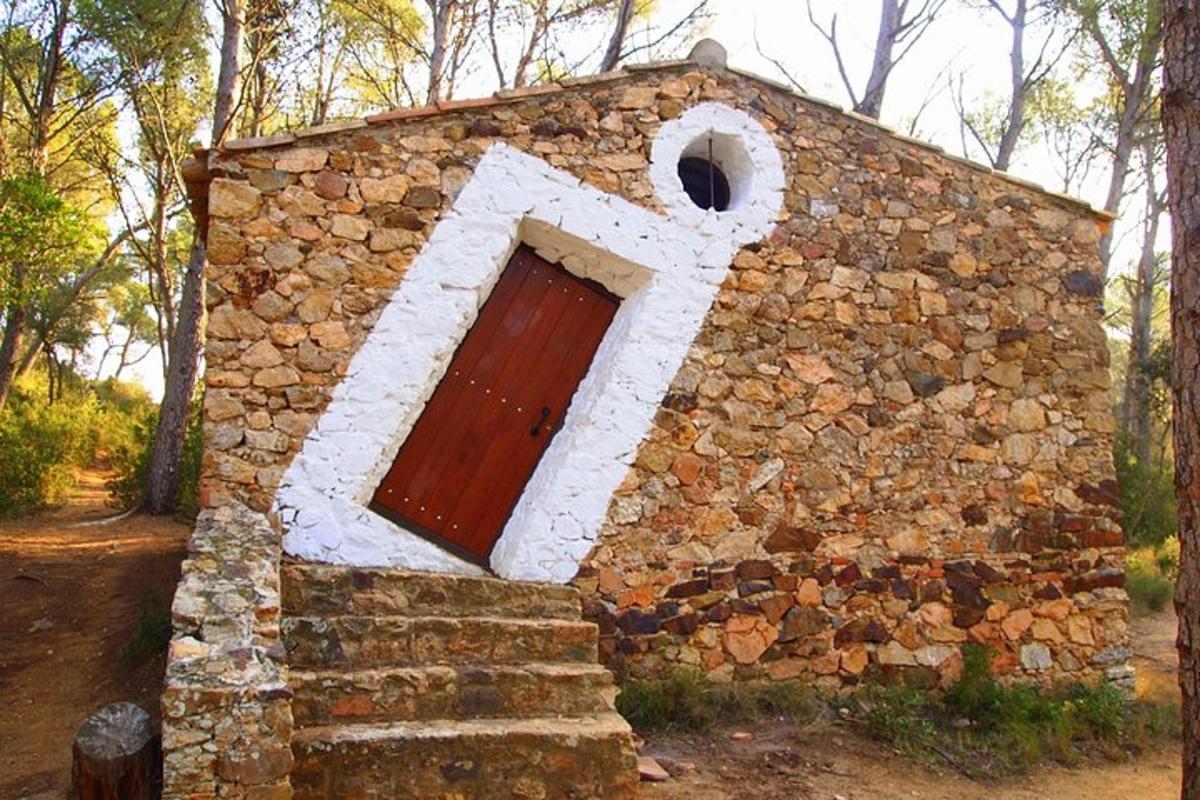 un piccolo edificio in pietra con una porta rossa