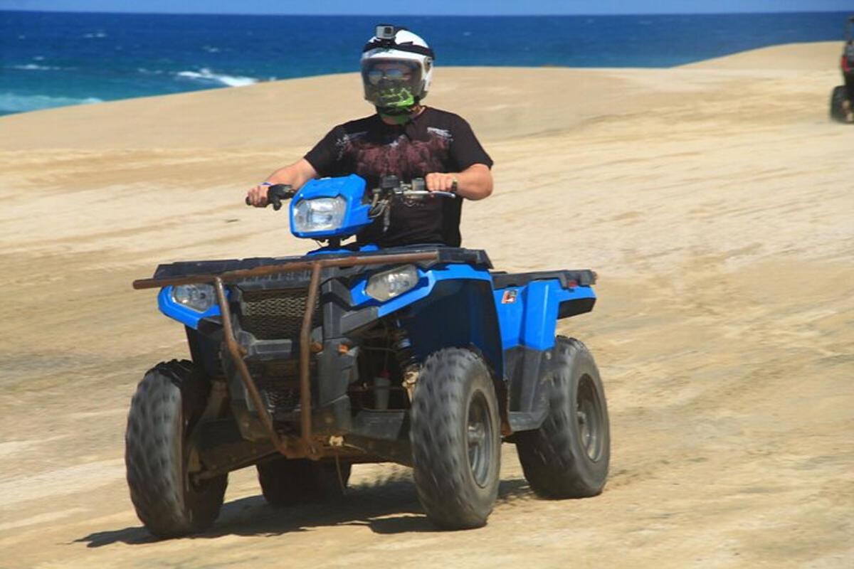 seorang lelaki menunggang kenderaan empat roda di pantai
