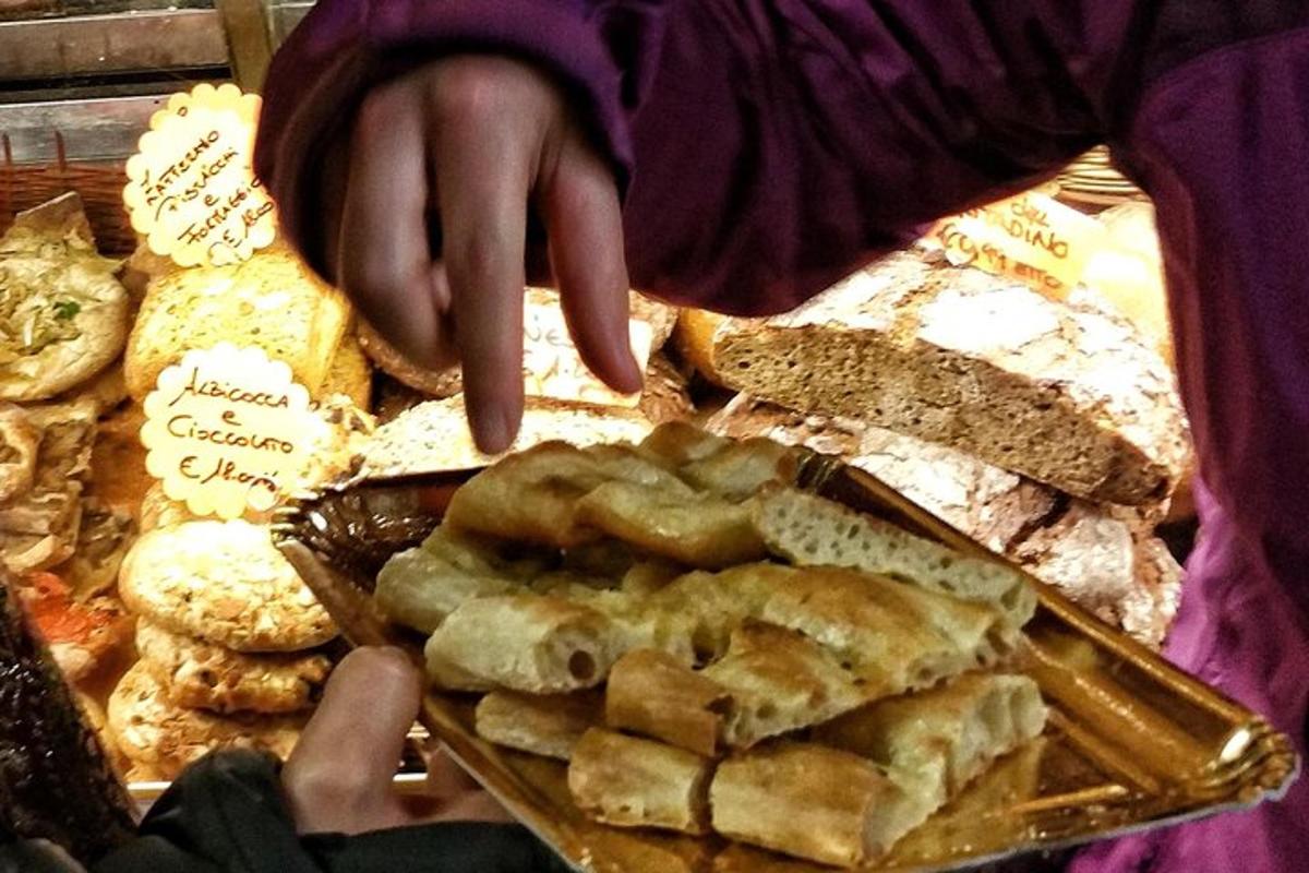 henkilö osoittaa leipä- ja leivonnaistarjotinta