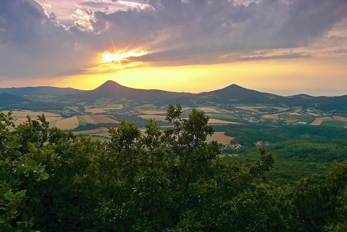 Una puesta de sol sobre un valle con montañas y árboles.