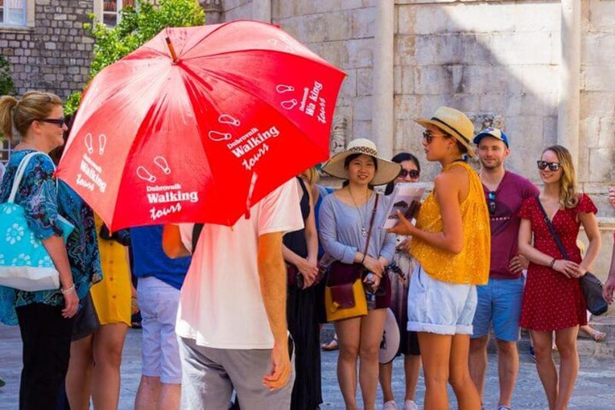un home que sosté un paraigua vermell davant d'un grup de persones