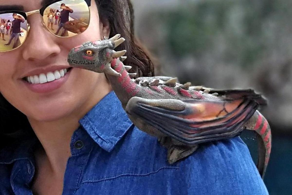eine Frau mit Sonnenbrille und einer Eidechse im Handschuh