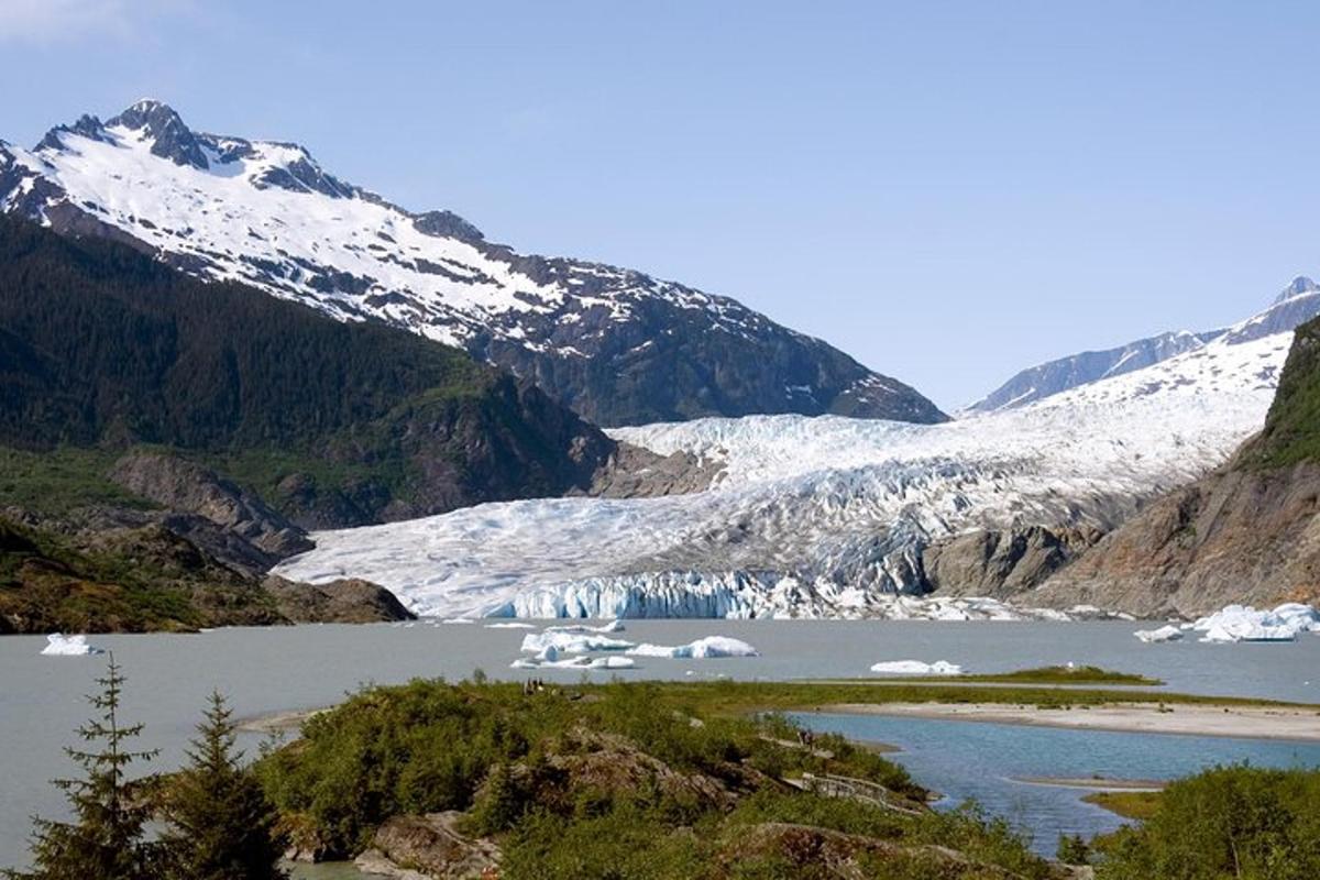 a glacier in a body of water with snow covered mountains