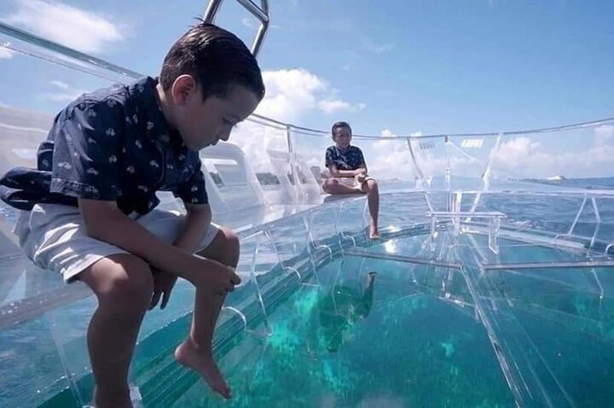 a young boy sitting on the glass floor of a boat