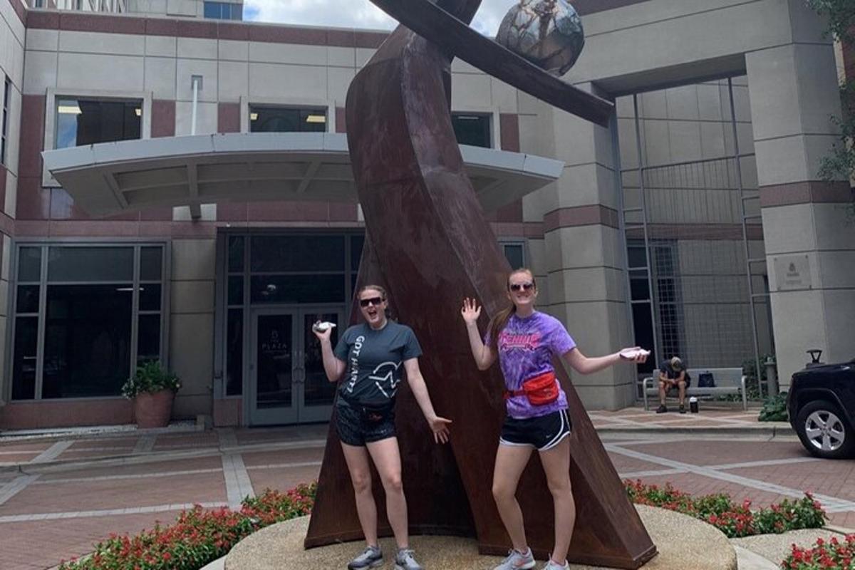 two people standing next to a statue in front of a building