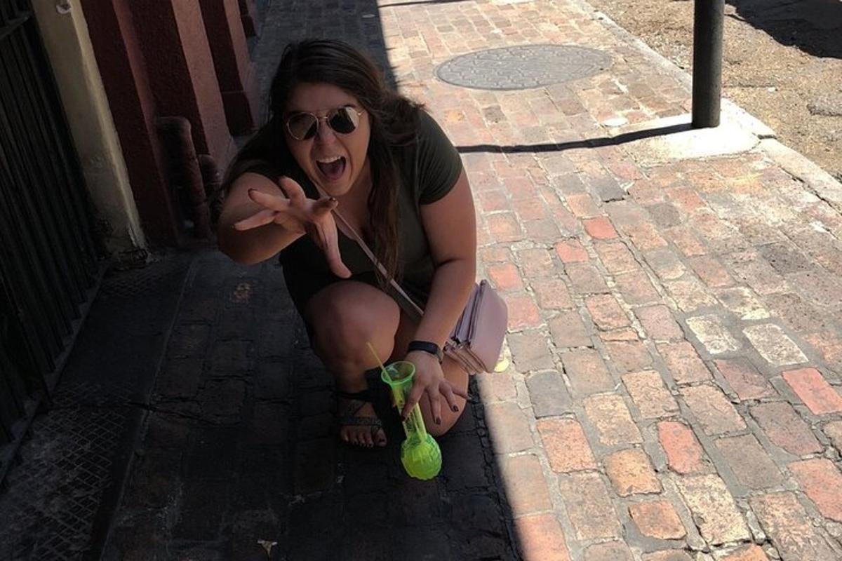 Una mujer en cuclillas sobre una acera de ladrillos sosteniendo una taza verde