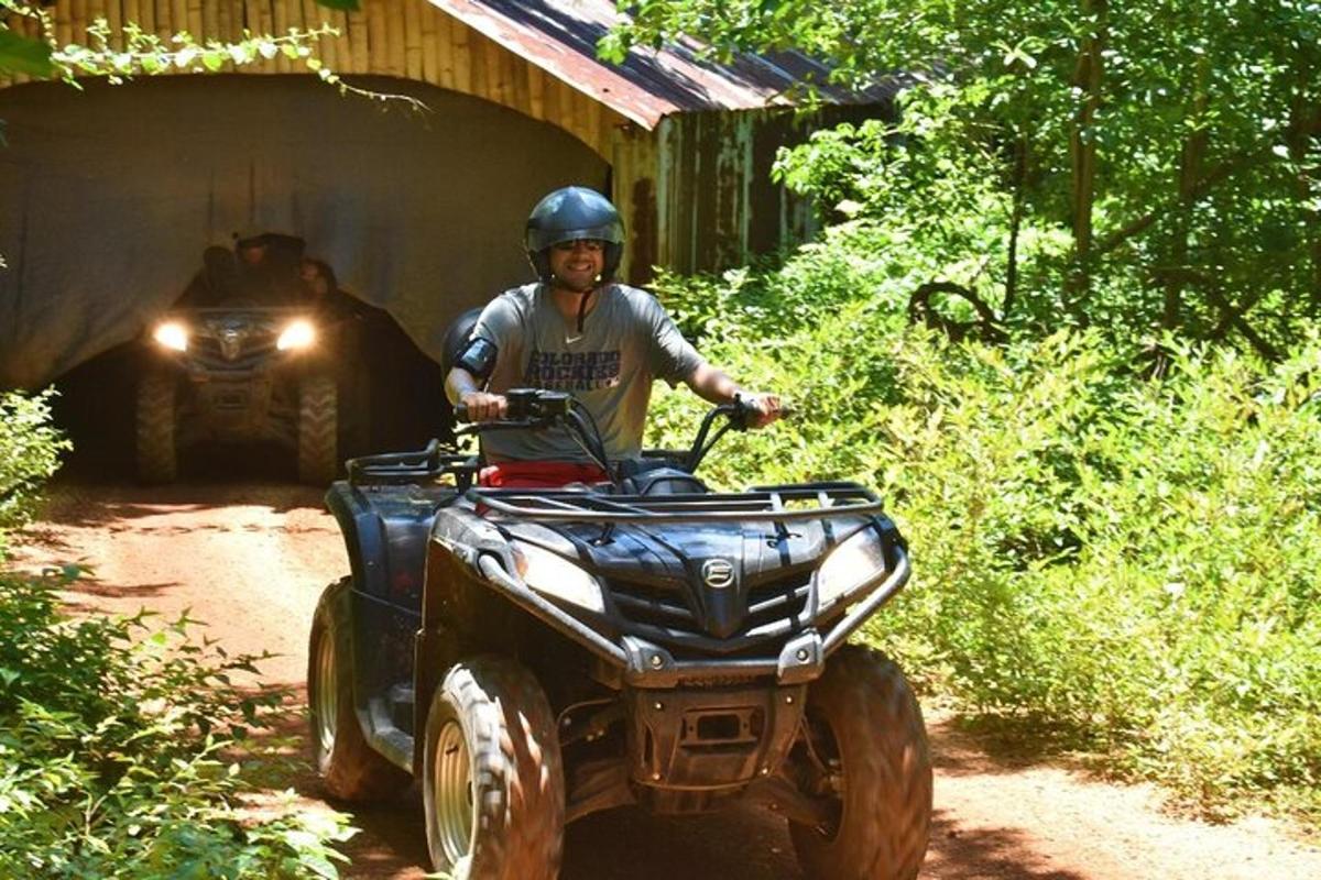 un uomo che guida un quad su un sentiero con un tunnel