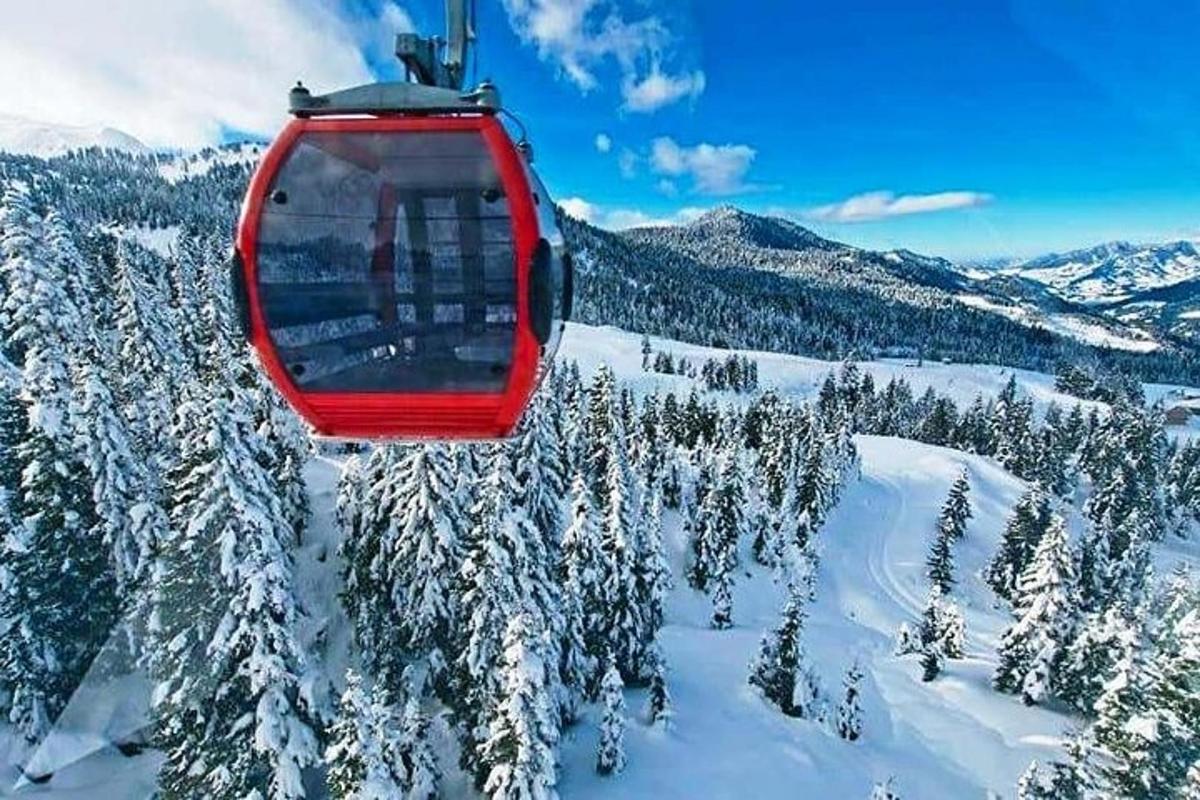 Červená lanovka letící nad zasněženou horou
