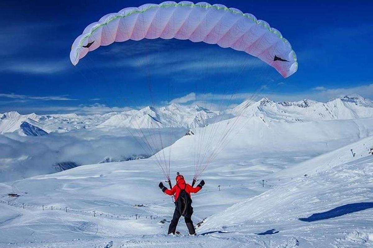 una persona che fa volare un aquilone sulla cima di una montagna innevata