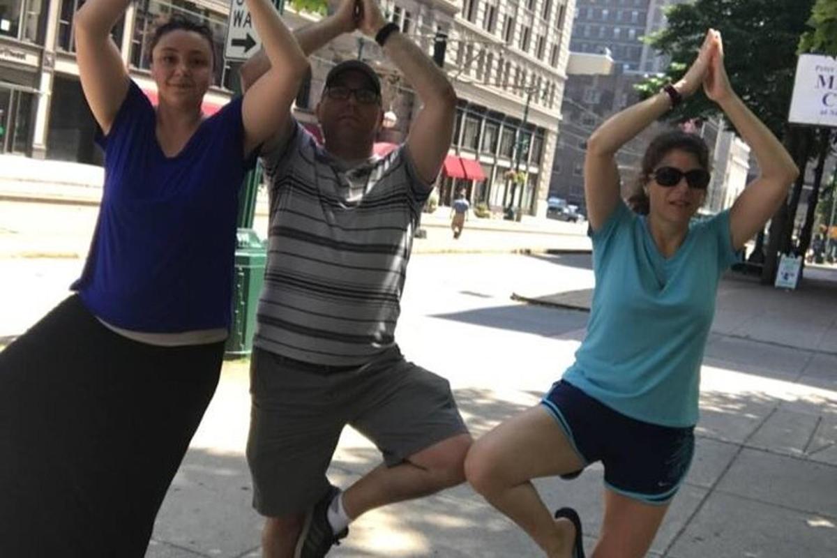 Un grupo de tres personas haciendo yoga en una calle de la ciudad.