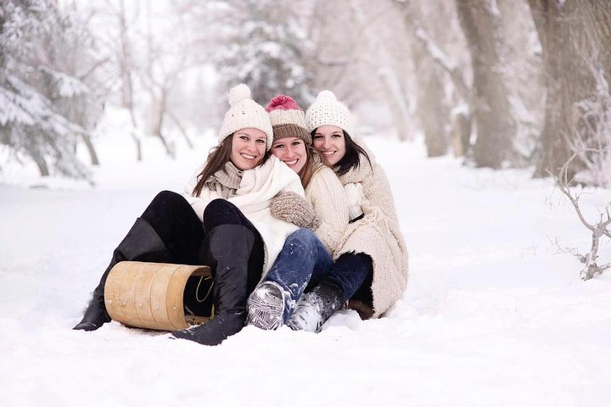 três meninas sentadas na neve com um barril