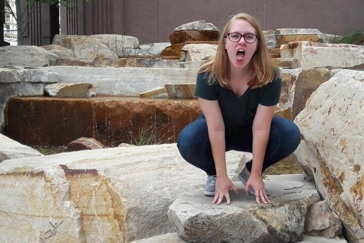 a woman sitting on a rock with her mouth open