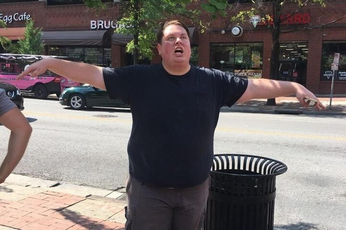 a man standing next to a trash can with his arms out