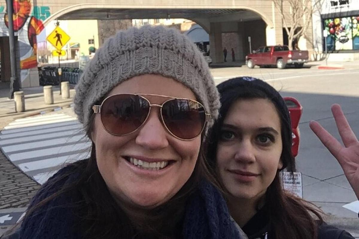 two women posing for a picture while wearing a hat and sunglasses