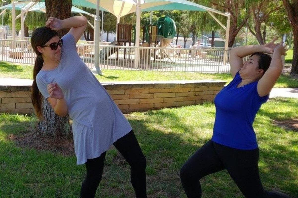 two women are practicing yoga in a park