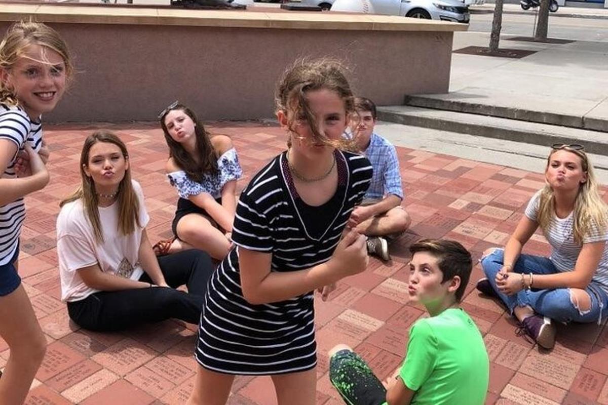 skupina mladých lidí sedících na chodníku