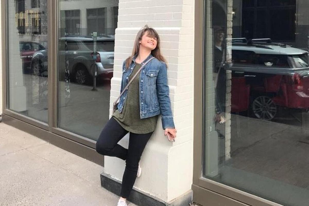 a young woman leaning against a wall in front of a store
