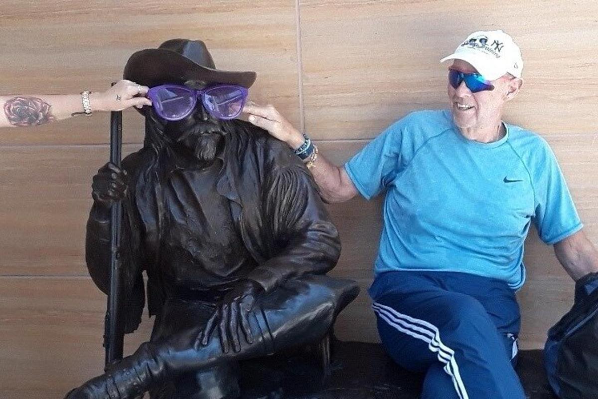 a man sitting next to a statue wearing purple glasses