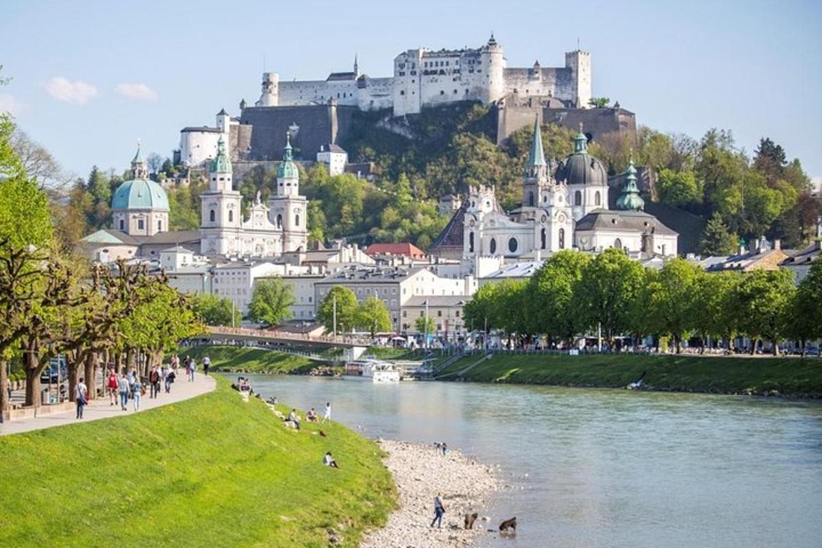 a group of people walking along a river with a castle