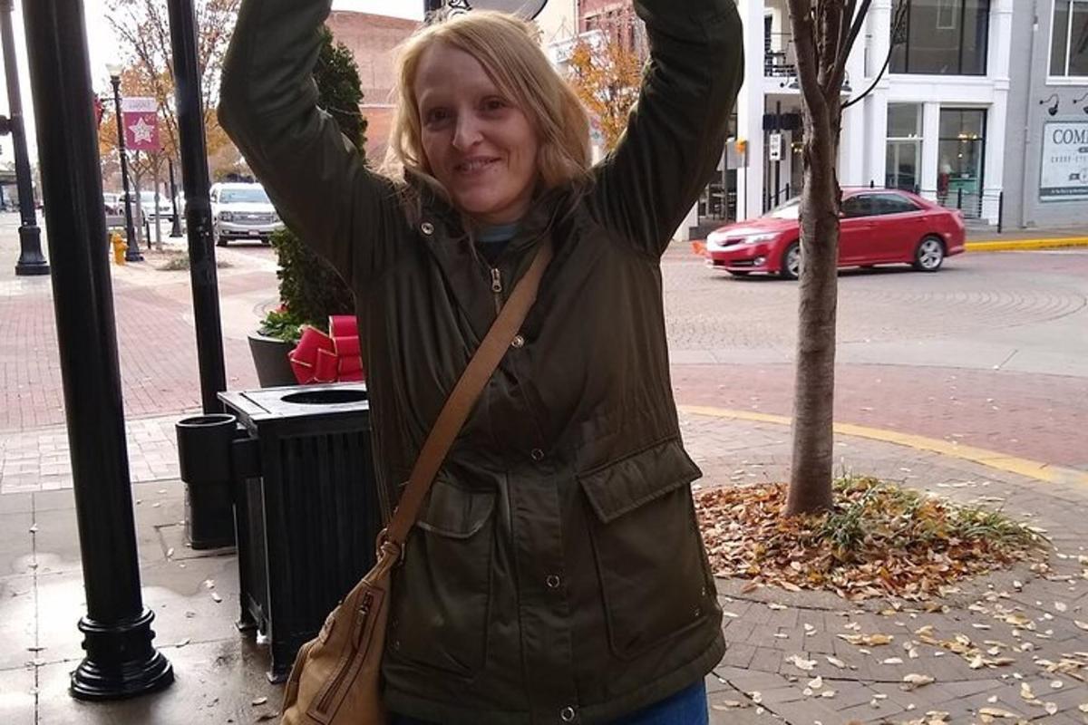 a woman standing on a street with her arms in the air