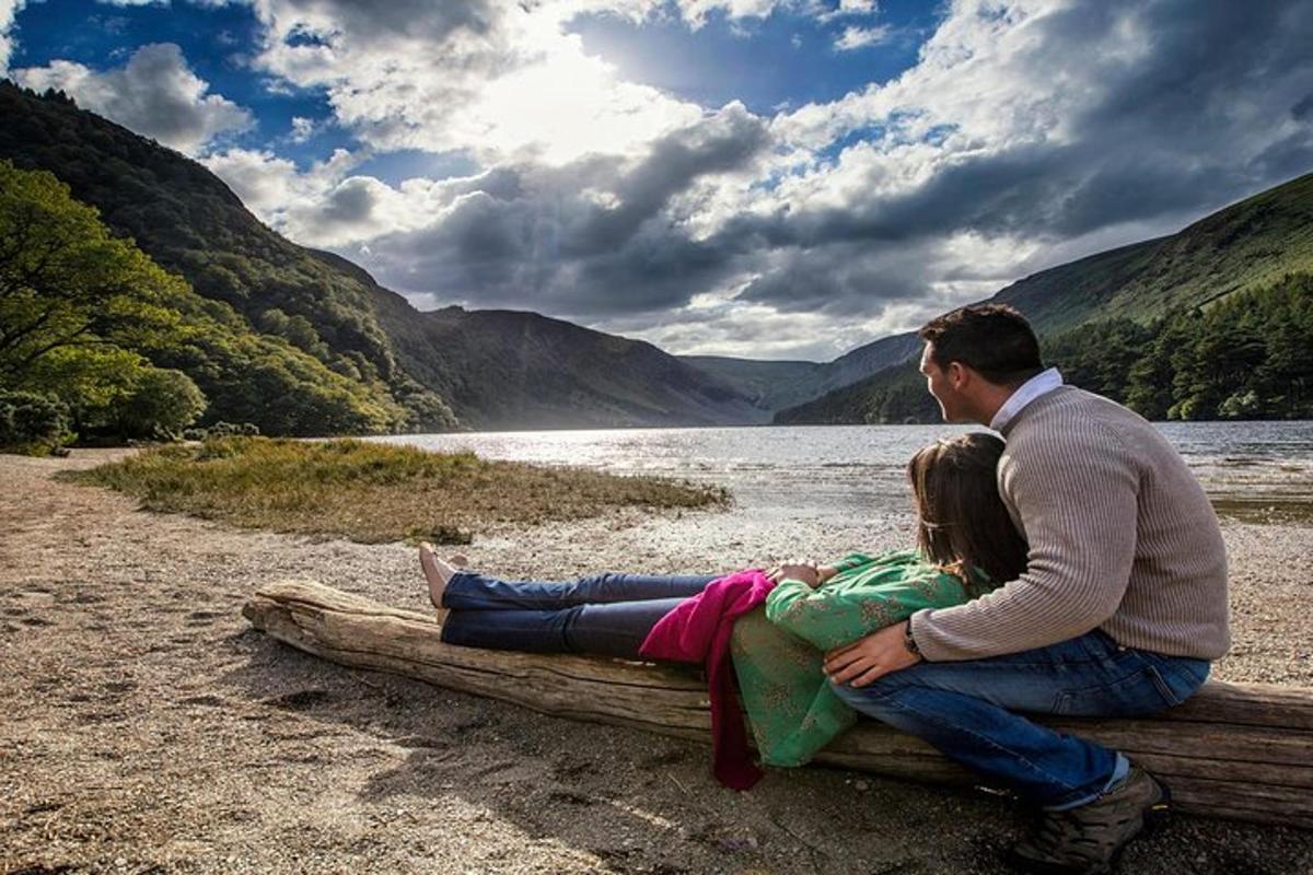 un uomo e una donna seduti su un tronco in riva a un lago